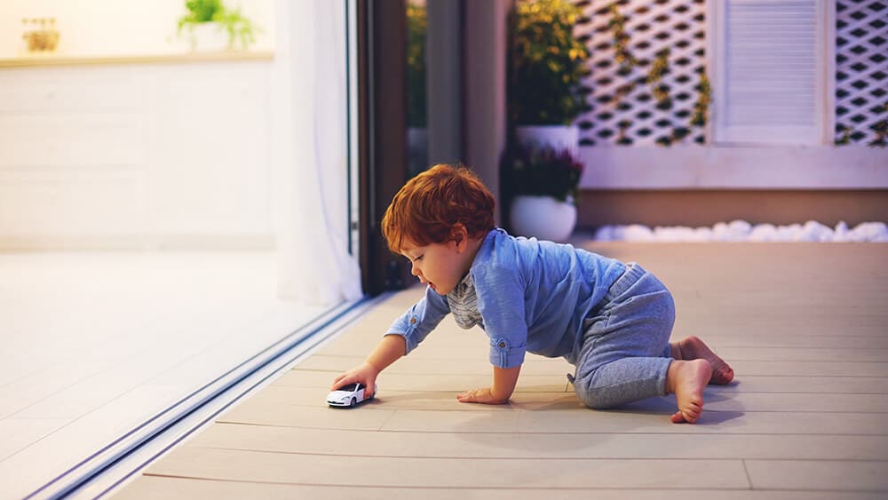 Child Playing with Toy Car Near Sliding Screen Door