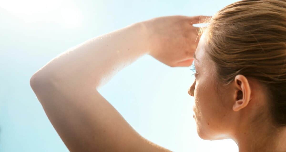 woman blocking sun out of her eyes with her arm/hand